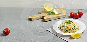 Traditional Arabic salad or Tabbouleh on white plate, cement background. Horizontal banner with copy space