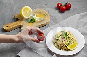 Traditional Arabic salad or Tabbouleh on white plate, healthy vegetarian dish with couscous on cement background