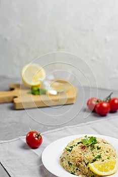 Traditional Arabic salad or Tabbouleh on white plate, healthy vegetarian dish with couscous on cement background