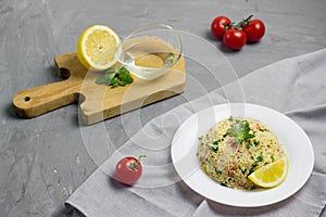 Traditional Arabic salad or Tabbouleh on white plate, healthy vegetarian dish with couscous on cement background