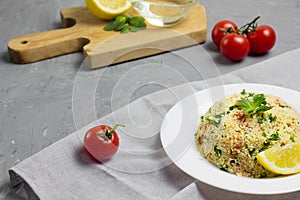 Traditional Arabic salad or Tabbouleh on white plate, healthy vegetarian dish with couscous on cement background