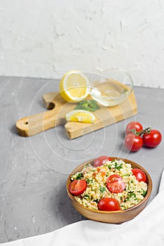 Traditional Arabic salad or Tabbouleh in wooden bowl, healthy vegetarian dish with couscous on cement background