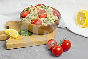 Traditional Arabic salad or Tabbouleh in wooden bowl, healthy vegetarian dish with couscous on cement background