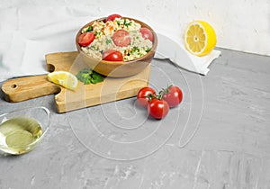 Traditional Arabic salad or Tabbouleh in wooden bowl, healthy vegetarian dish with couscous on cement background