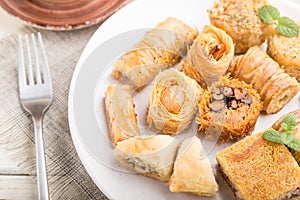 Traditional arabic sweets kunafa, baklava  and a cup of coffee on a white wooden background. side view, selective focus