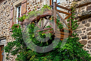 Traditional architecture stone house in french village. Window balcony garden decorated with a mix of many plants and