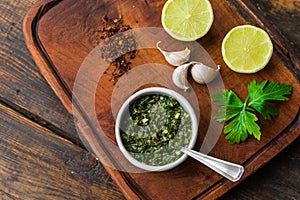 Traditional Argentinian chimichurri sauce against wooden background.