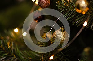 Traditional artificial Christmas tree with gold ball ornament and glowing colorful lights in background with copy space. Soft