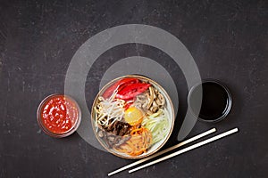 Traditional Asian Bibimbap dish with rice and vegetables on dark background