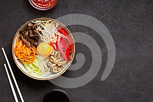 Traditional Asian Bibimbap dish with rice and vegetables on dark background