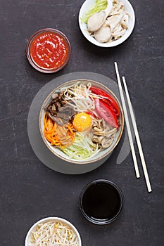 Traditional Asian Bibimbap dish with rice and vegetables on dark background