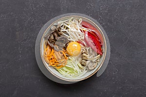 Traditional Asian Bibimbap dish with rice and vegetables on dark background. Central composition