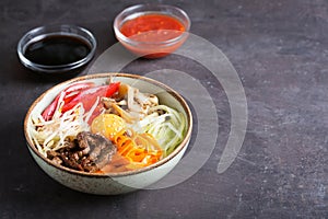 Traditional Asian Bibimbap dish with rice and vegetables on dark background with copy space