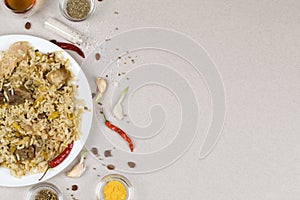 Traditional asian dish - pilaf from from rice, vegetables and meat in white plate on gray background