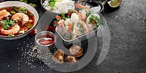 Traditional Asian food table. Spring roll, rice, shrimp, sushi, vegetables, meat on dark background