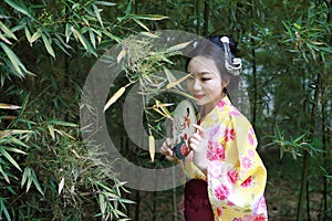 Traditional Asian Japanese beautiful Geisha woman bride wears kimono hold a fan in a summer nature