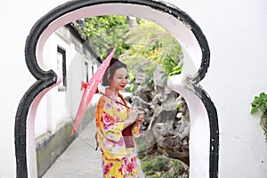 Traditional Asian Japanese beautiful Geisha woman bride wears kimono hold a umbrella in a summer nature