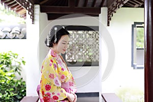 Traditional Asian Japanese beautiful Geisha woman bride wears kimono with red umbrella on hand in a summer nature