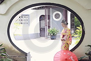 Traditional Asian Japanese beautiful Geisha woman wears kimono hold a umbrella on hand in a summer graden