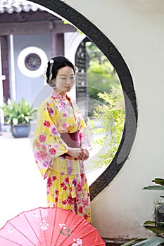 Traditional Asian Japanese beautiful Geisha woman wears kimono hold a umbrella on hand in a summer graden