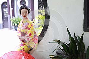 Traditional Asian Japanese beautiful Geisha woman wears kimono hold a umbrella on hand in a summer nature