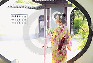 Traditional Asian Japanese beautiful Geisha woman wears kimono hold a umbrella on hand in a summer nature