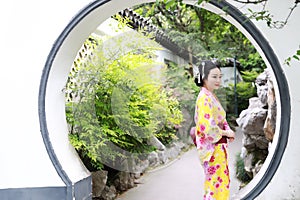 Traditional Asian Japanese beautiful woman bride wears kimono with red umbrella in outdoor spring garden