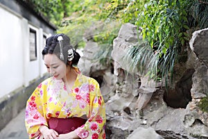 Traditional Asian Japanese beautiful woman wears kimono in a spring garden park stand by bamboo enjoy free time