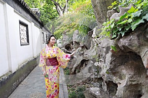 Traditional Asian Japanese beautiful woman wears kimono in a spring garden park stand by bamboo enjoy free time