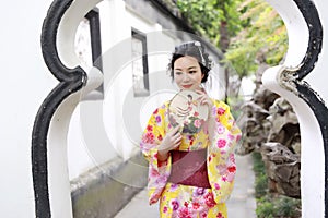 Traditional Asian Japanese beautiful woman wears kimono in a spring garden park stand by bamboo enjoy free time fan
