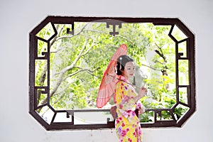 Traditional Asian Japanese woman bride hold a red umbrella smiling in a outdoor garden