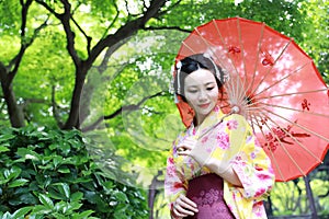 Traditional Asian Japanese woman in a garden hold a red umbrella