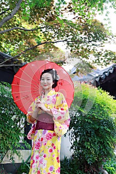 Traditional Asian Japanese woman in a garden hold a red umbrella