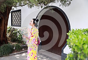 Traditional Asian Japanese woman Geisha wearing kimono hold a fan play in a graden