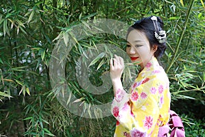 Traditional Asian Japanese woman with kimono Japanese bride smiling stand by bamboo in a spring park