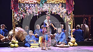 Traditional Asian puppet show with performers in cultural attire and musical instruments on stage