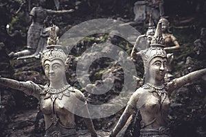 Traditional Asian stone sculptures of women in traditional suits in garden on tropical island in Thailand