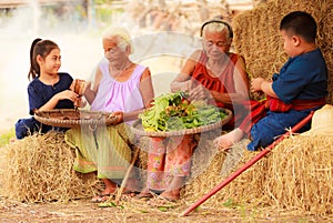 Traditional Asian Thai rural daily life, grandchildren in cultural costumes help their seniors preparing local food ingredients
