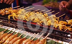 Traditional Asian Thai street food and fast food, delicious grilled squid calamari skewers in food market stall background.
