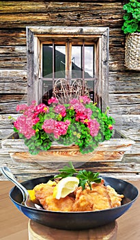 Traditional austrian food Wiener schnitzel against traditional cottage in Kaprun, Austria