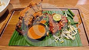 Traditional Ayam Taliwang indonesian cuisine with Vegetable Mash and Curry Soup on Banana Leaf