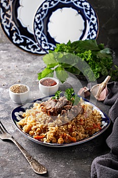 Traditional azian pilaf in ornament plate on gray background