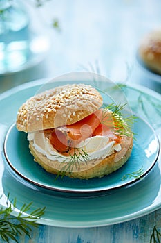 Traditional bagel with cream cheese, smoked salmon and fresh fennel served on a blue plate