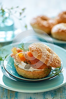 Traditional bagel with cream cheese, smoked salmon and fresh fennel served on a blue plate