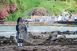 Traditional bagpiper in full dress code near Pennan