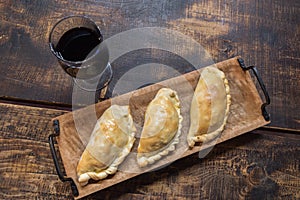 Traditional baked Argentine and Uruguay empanadas savoury pastries with meat beef stuffing against wooden background photo