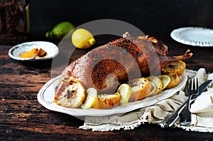 Traditional baked duck with apples and lemon on a dark wooden table