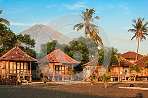 Traditional balinese wooden bungalows on beach with Agung volcano