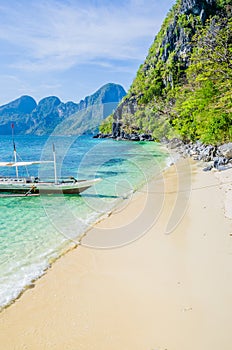 Traditional banca boat in clear water at sandy beach near El Nido, Philippines