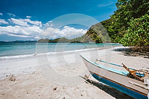 Traditional banca boat in front of remote tropical beach with exotic blue lagoon. El Nido, Philippines